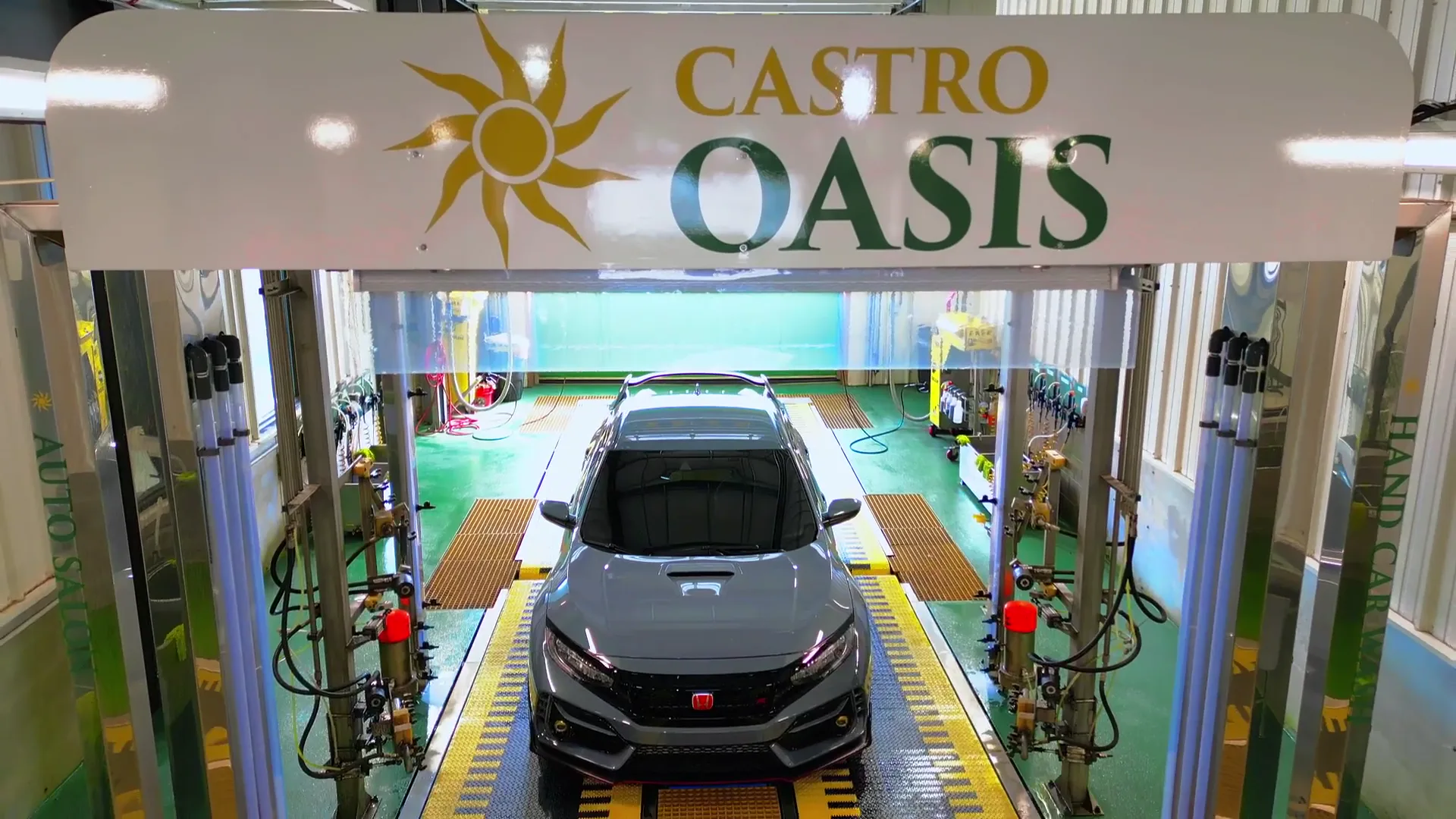 A Honda Civic Type R centred under the branded Castro Oasis wash arch, the pillars reading Auto Salon and Hand Car Wash.